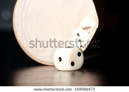 close-up of white dice on old wood black table near a container