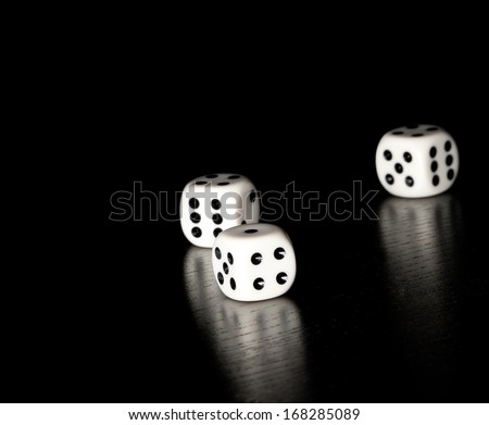 three white dice on old wood black table on black background with space for text