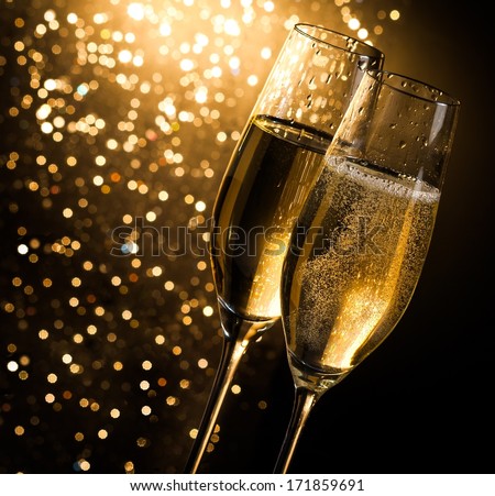 champagne flutes with golden bubbles on dark golden light bokeh background with space for text