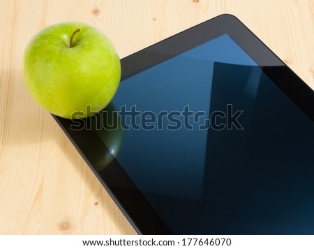 digital tablet pc and green apple on wood table, concept of learn new technology