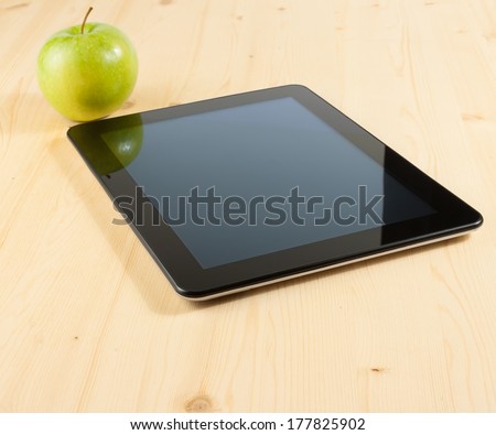 digital tablet pc near green apple on wood table, concept of learn new technology