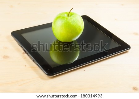 green apple on digital tablet pc on wood table, concept of learn new technology