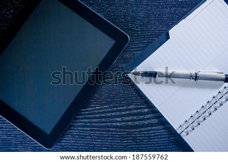 digital tablet pc near notes in the office on wood black table, concept of new technology