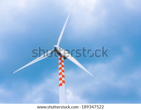 wind turbine in movement under blue sky and clouds with space for text