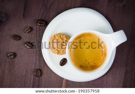 top of view of cup of cup of espresso coffee and biscuit near coffee beans on old wood