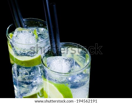 glasses with cocktail and ice with lime slice on black background with space for text, disco club atmosphere