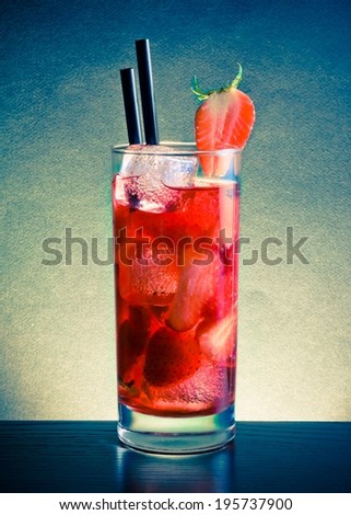 Strawberry cocktail with ice on wood table on blue light disco club atmosphere
