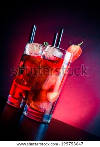 glasses of strawberry cocktail with ice on wood table on blue and pink light, disco club atmosphere
