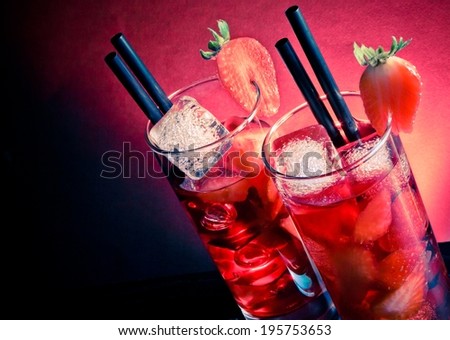 Strawberry cocktail with ice on wood table and space for text on blue and pink light disco club atmosphere