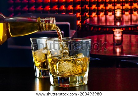 barman pouring whiskey in a lounge bar on wood table