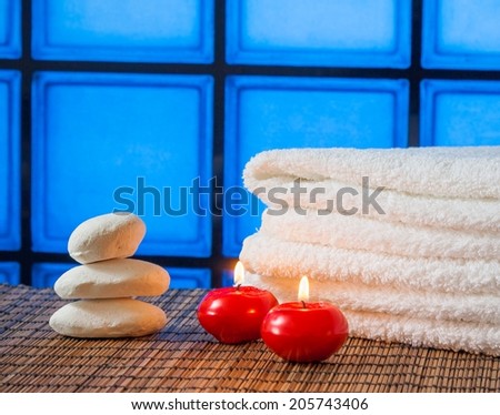 Spa massage border background with towel stacked stone and red candles on blue tiles background warm atmosphere