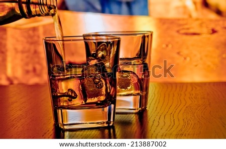 silhouette of whiskey glasses with ice on bar table on warm atmosphere lounge bar concept
