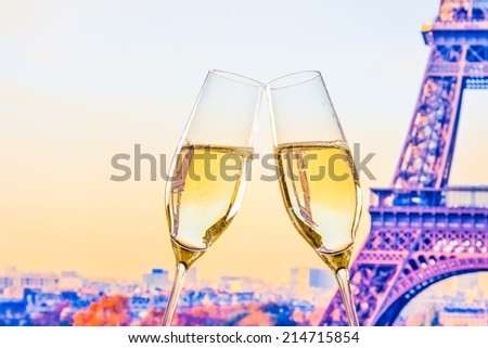 a pair of champagne flutes with golden bubbles make cheers on blur tower Eiffel background valentine day concept