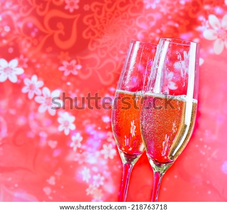 a pair of champagne flutes with golden bubbles on red vintage background love concept