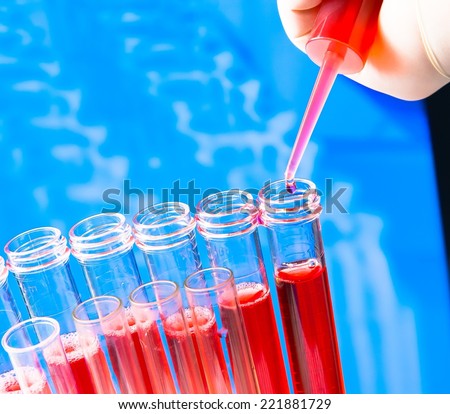 closeup of test tubes with pipette on red liquid on blur laboratory background