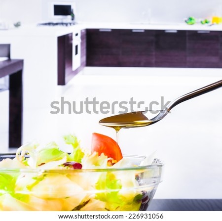 spoon with olive oil on italian fresh salad and tomato on kitchen background nutrition concept