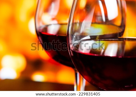 detail of two red wine glasses against colorful unfocused lights background, festive and fun concept