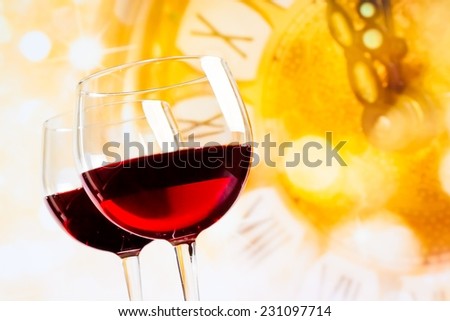 two red wine glasses against golden clock background, festive and fun concept