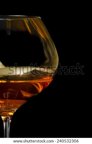 snifter of brandy in elegant glass with space for text on black background