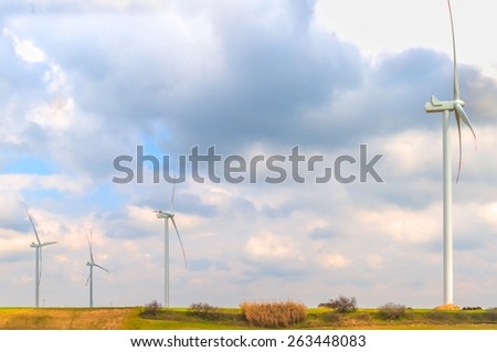 wind energy turbines are one of the cleanest, renewable electric energy source, under blue sky with white clouds. Electricity is generated by electric generators hidden inside turbine