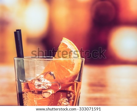 detail of glass of spritz aperitif aperol cocktail with orange slices and ice cubes on bar table, vintage atmosphere background, lounge bar concept