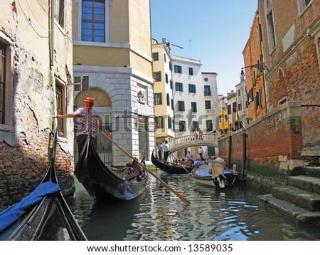 The gondoliers floats on the channel of Venice with tourists