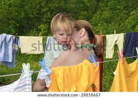 mother with sleepy kid at the rural yard with drying clothes