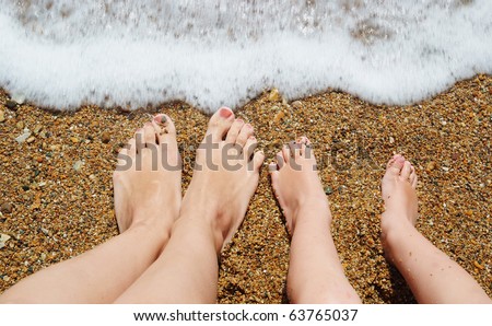 feet of child and mom in the sea waves