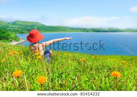 happy girl on the flower meadow against the sea landscape