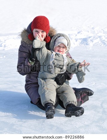 happy family of mother with baby playing in the snow winter park