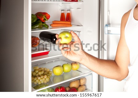 Hand Reaching for Green Apple in Refrigerator