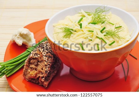Cauliflower soup in orange bowl