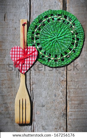 Wooden kitchen fork and green wicker napkin on a wooden counter with copyspace