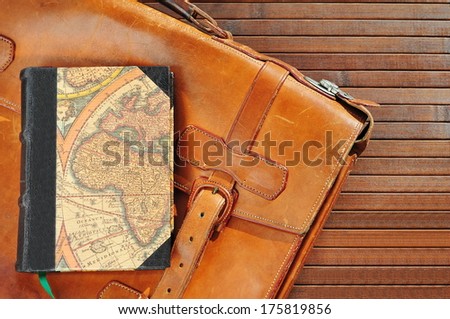 Vintage leather briefcase with old book and map
