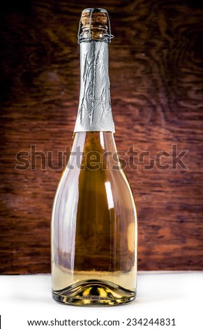 Closed bottle of sparkling wine on a wooden background