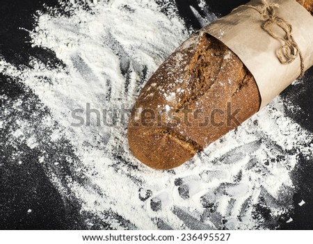 black long loaf on a dark background with flour