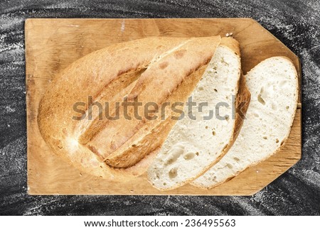 sliced white long loaf on a dark background with flour