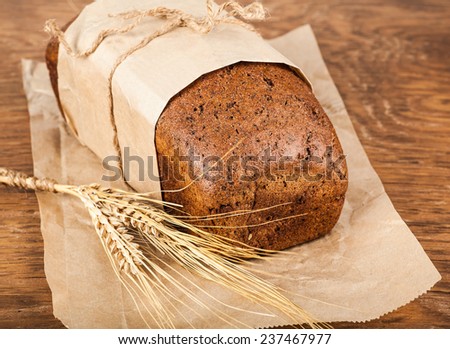 bread in a paper packing with ears of wheat on the wooden background