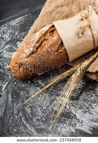 long loaf with ears of wheat on a dark background