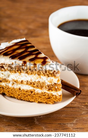 chocolate cake on a plate and black coffee on a wooden background