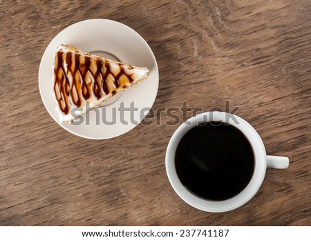 piece of chocolate cake on a plate and black coffee on a wooden background