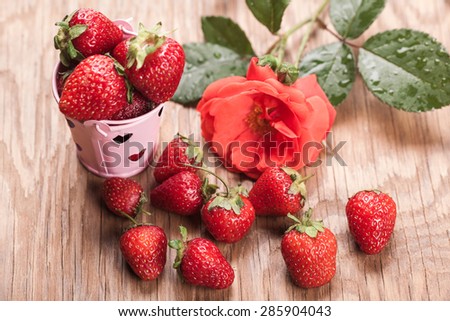 bucket of strawberries and rose on a wooden background