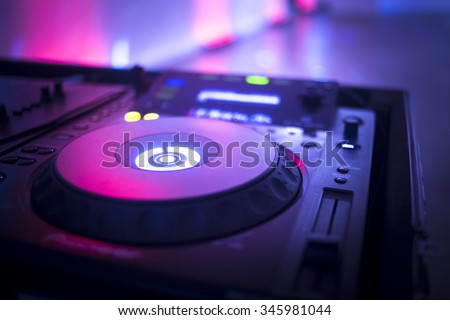 DJ console cd mp4 deejay mixing desk Ibiza house music party in nightclub with colored disco lights.