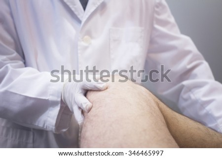 Male Traumatologist orthopedics surgeon doctor examining middle aged man patient to determine injury, pain, mobility and to diagnose medical treatment in knee meniscus cartilage injury.
