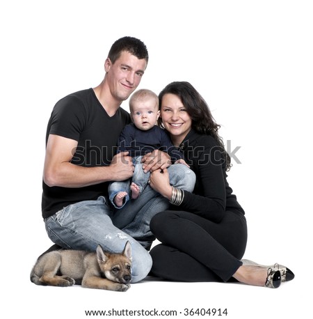 Portrait of young family with baby boy and 2 months old wolf cub in front of white background, studio shot