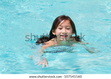 Funny little girl swims in a pool