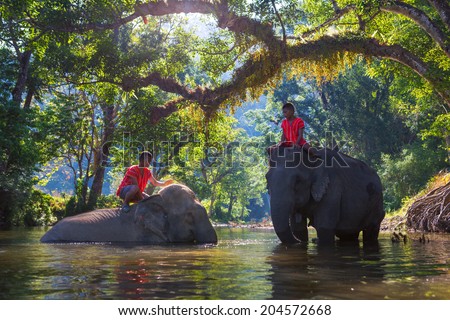 SANGKHLABURI , KANJANABURI, THAILAND-MARCH 23 : An unidentified man shows how to bathe an elephant in a river show in Sangkhlaburi, Kanjanaburi, Thailand on MARCH 23, 2013