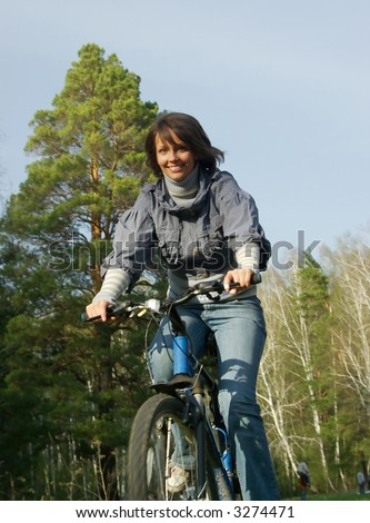 smiling girl riding on a bicycle in the forest wheel blur