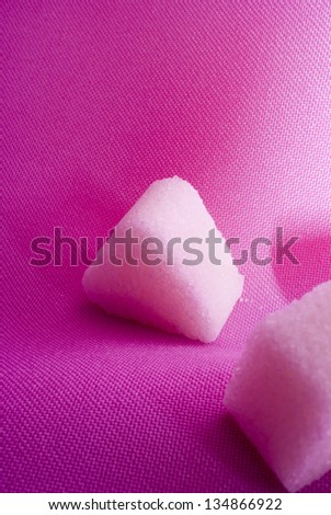 Three art-shaped pieces of sugar on a pink background