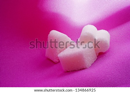 Three art-shaped pieces of sugar on a pink background